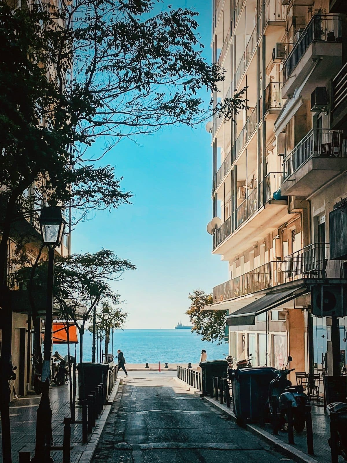 A city street running downhill between apartment blocks to the waterfront