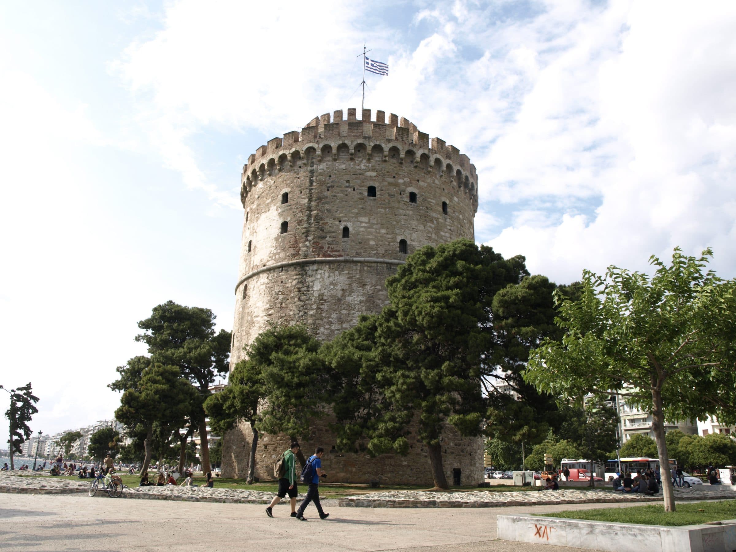Ο Λευκός Πύργος από το πάρκο στη βάση του, με την ελληνική σημαία και τα πεύκα